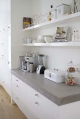 witte keukenkasten met witte planken en broodtrommel